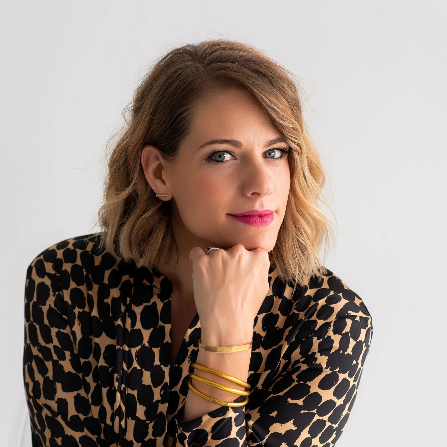Woman wearing a leopard print dress with gold accessories against a white background